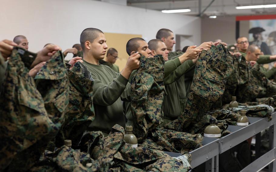 Marine Corps recruits fold their uniforms during their first fitting at Marine Corps Recruit Depot San Diego, Dec. 14, 2022.