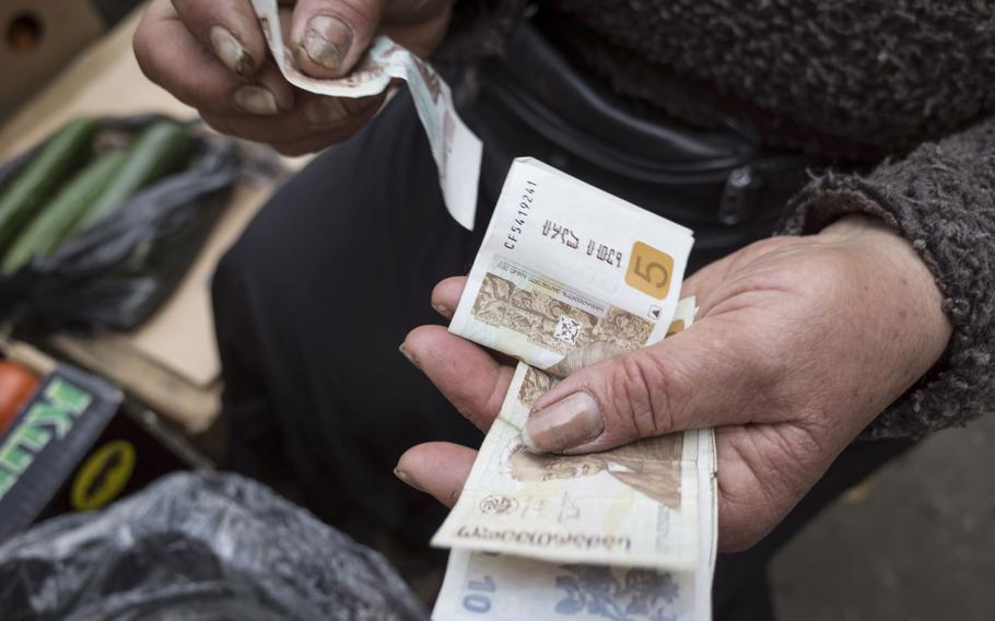 A market trader counts lari banknotes at a stall in Tbilisi, Georgia, on April 15, 2014. 