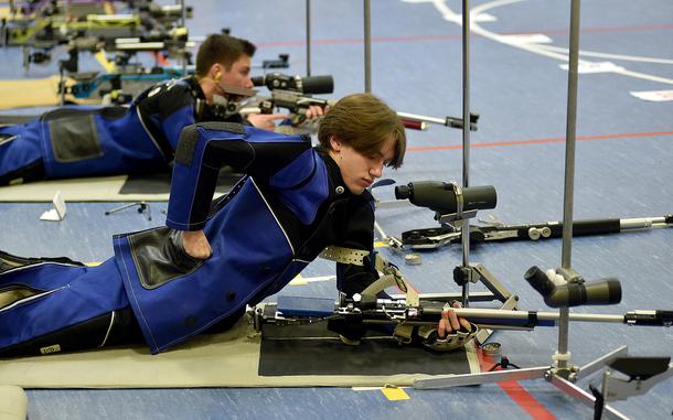Ansbach's Alexander Pohlman reaches into his pocket while in the prone position during the DODEA European marksmanship championship Saturday at WIesbaden High School in Wiesbaden, Germany. In the background, teammate Collin Robertson takes aim.