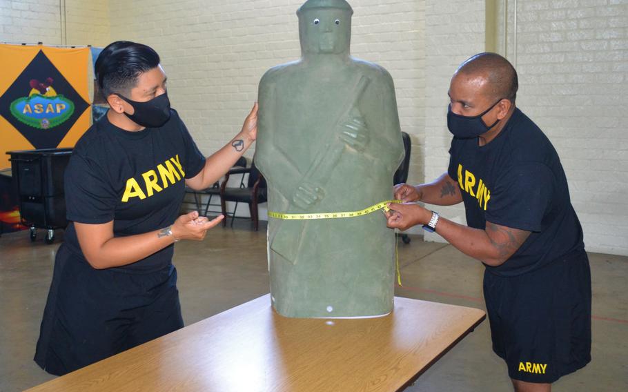 Soldiers demonstrate how to perform a waist measurement during a height and weight test June 3, 2020. The service’s senior enlisted leader proposed that soldiers who score a 540 or higher on the Army Combat Fitness Test won’t need to be measured against the height and weight standards.