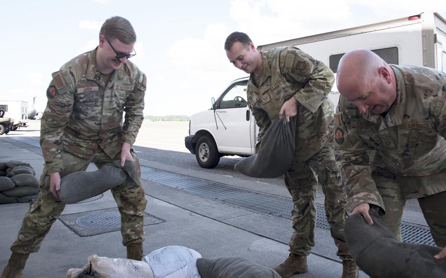 Staff Sgt. Coye Jurek, of Gonzales, Texas, left; Staff Sgt. Tracy Beasley, of Philidelphia and Tech. Sgt. Grant Carlson, of Kansas City, Mo., place sandbags Aug. 11, 2023, ahead of Typhoon Lan's expected arrival at Yokota Air Base, Japan.