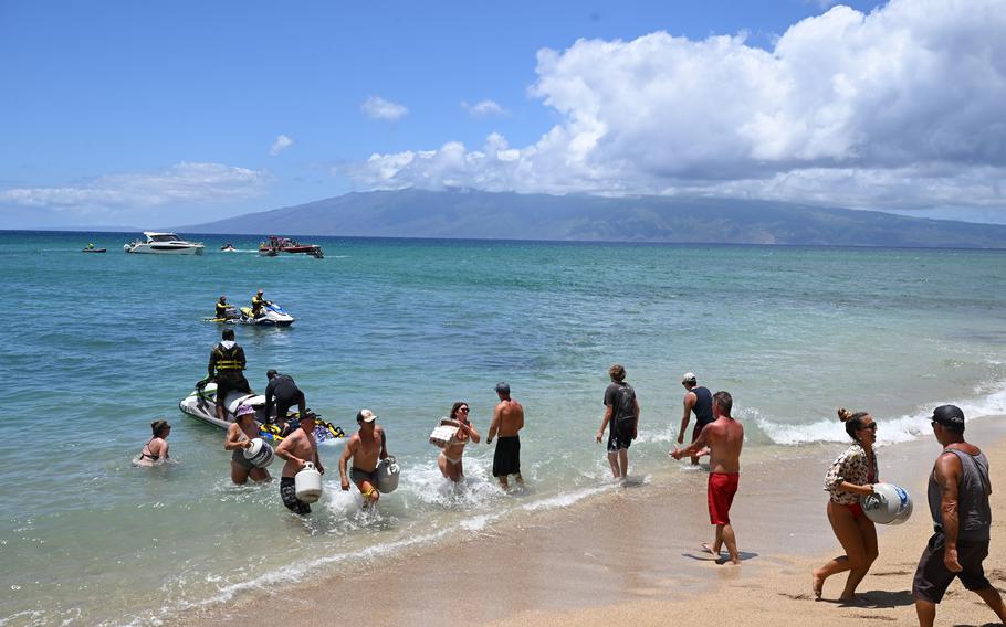 People retrieve propane tanks and other supplies brought in by boats on Aug. 12, 2023, in Kahana, Hawaii. 