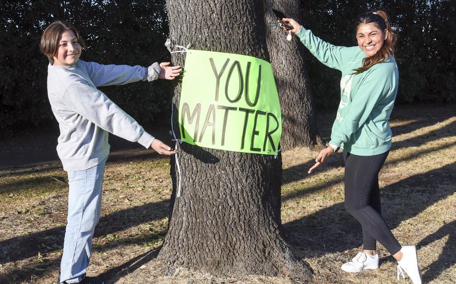 Air Force spouse Alma Stover and her son, Jett Stover, 12, pose with an inspirationl poster they created and posted near an exercise trail at Yokota Air Base, Japan, Feb. 16, 2023. 