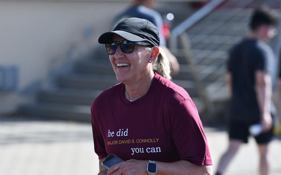 A woman in a red T-shirt and baseball cap smiles.