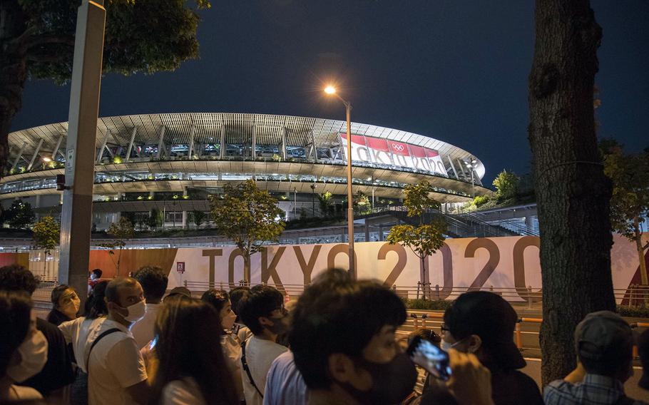 People flock near new National Stadium during the opening ceremony for the Tokyo Olympics, Friday, July 23, 2021. 