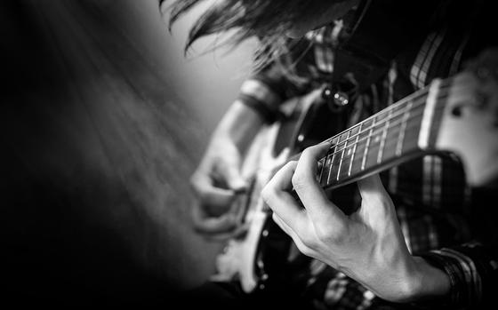 Electric guitar playing. Young men playing electric guitar. Black and white closeup Photography.