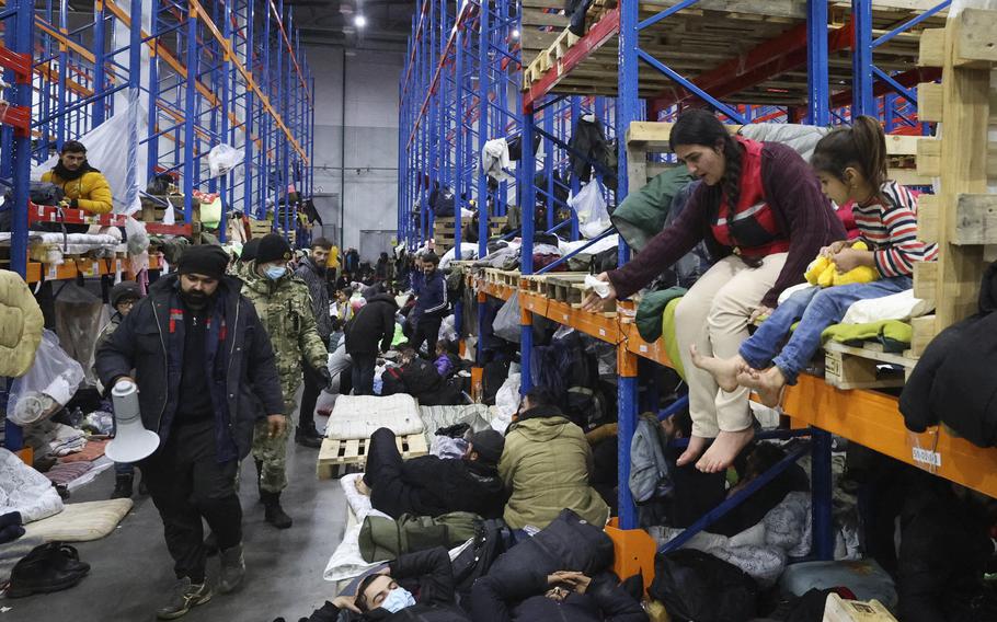 Migrants settle in a logistics center at the checkpoint “Kuznitsa” at the Belarus-Poland border near Grodno, Belarus, on Friday, Nov. 19, 2021. Polish authorities said Friday there are no more migrants camping along the Belarus side of the European Union’s eastern border, but attempts at illegally crossing into the bloc’s territory are continuing and becoming more aggressive. Hundreds of Iraqis flew back home Thursday from Belarus after abandoning their hopes of reaching the EU.