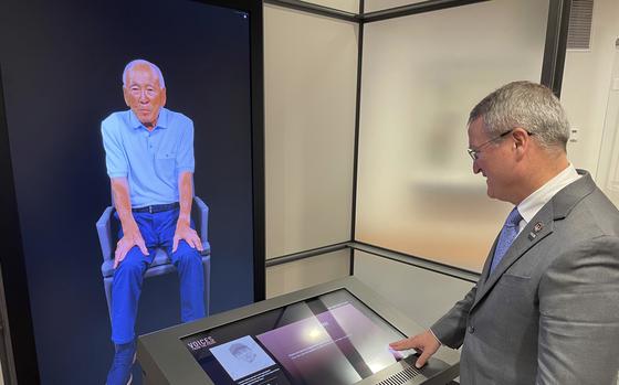Peter Crean of the National WWII Museum in New Orleans stands at an interactive exhibit with an image of Japanese-American WWII veteran Lawson Ichiro Sakai, who served in the U.S. Army, Tuesday, March 19, 2024. Sakai and 17 other people, including World War II combat veterans, a military nurse, an aircraft factory worker and a USO performer, made extensive video-recordings about their lives and service as part of an interactive exhibit opening at the museum March 20.