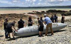 U.S. military personnel recover an F/A-18 Super Hornet’s empty fuel tank that washed ashore in Higashi Village, Okinawa, Wednesday, June 1, 2022. 