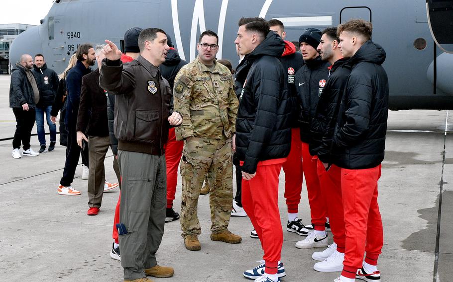 Col. Dan Cooley, wing commander of the 521st Air Mobility Operations Wing, left, and Maj. David Tart, center, talk with 1. FC Kaiserslautern players on the flight line, March 23, 2023, at Ramstein Air Base, Germany.