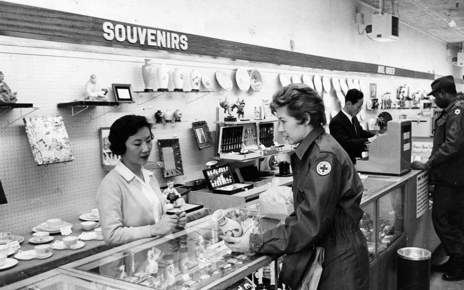 A woman stands behind a souvenir counter