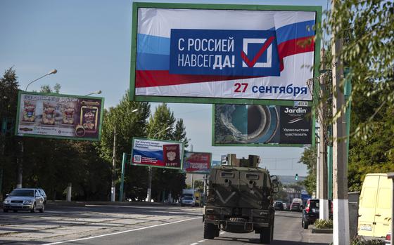 FILE - A military vehicle drives along a street with a billboard that reads: "With Russia forever, September 27", prior to a referendum in Luhansk, Luhansk People's Republic controlled by Russia-backed separatists, eastern Ukraine, Thursday, Sept. 22, 2022. Four occupied regions in Ukraine are set to start voting Friday Sept. 23, 2022 in Kremlin-engineered referendums on whether to become part of Russia, setting the stage for Moscow to annex the areas in a sharp escalation of the nearly seven-month war. (AP Photo/File)
