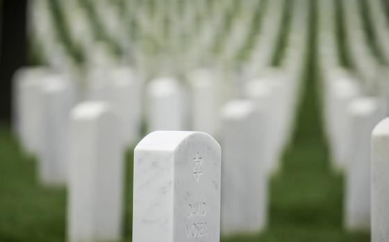 An in-focus tombstone with the Star of David engraved on it, while other tombstones are lined up out-of-focus behind it.