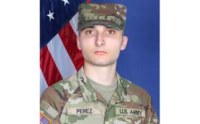 Perez in an official Army photo wearing fatigues with an American flag behind him.