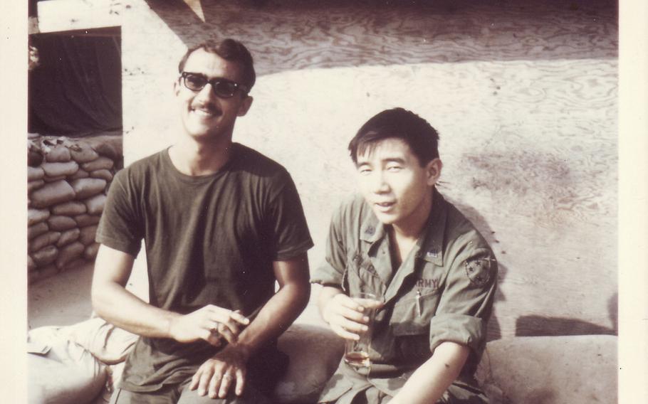 In this photo provided by William Fong, Fong is pictured sitting with a fellow soldier at a U.S. military base in Vietnam.