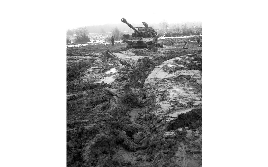 A black and white, vertical photo of a tank in a muddy area.