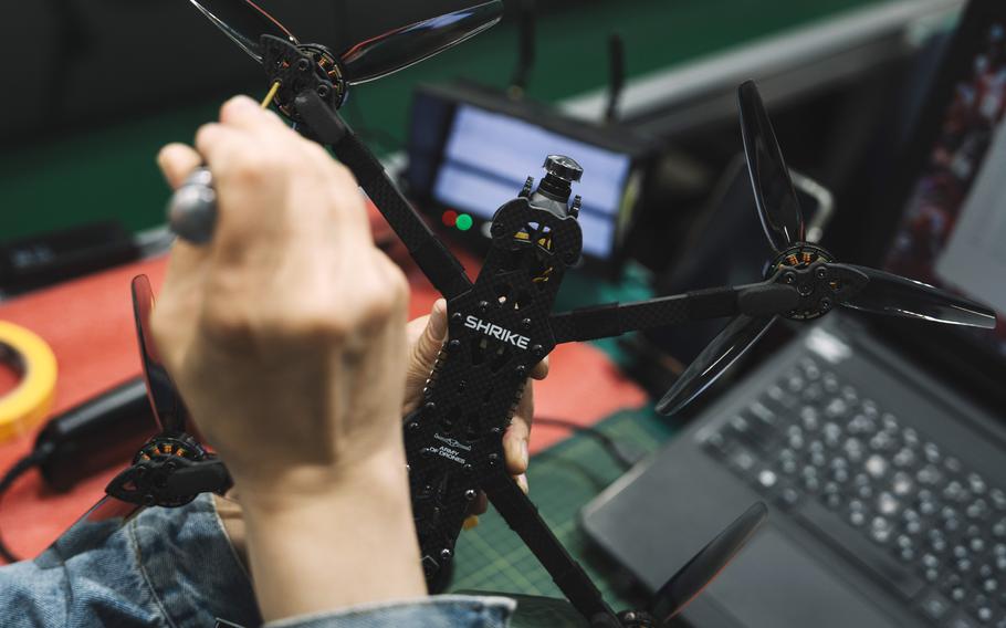 A technician’s hands, with a screwdriver, work on a drone.