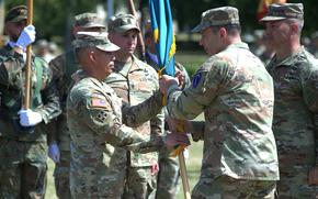 Soldiers hold onto a flag during a change of command.