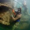 Two divers in scuba gear survey the wreckage of a ship under water.