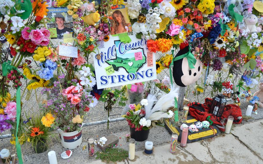 Flowers, photos and candles on a fence.