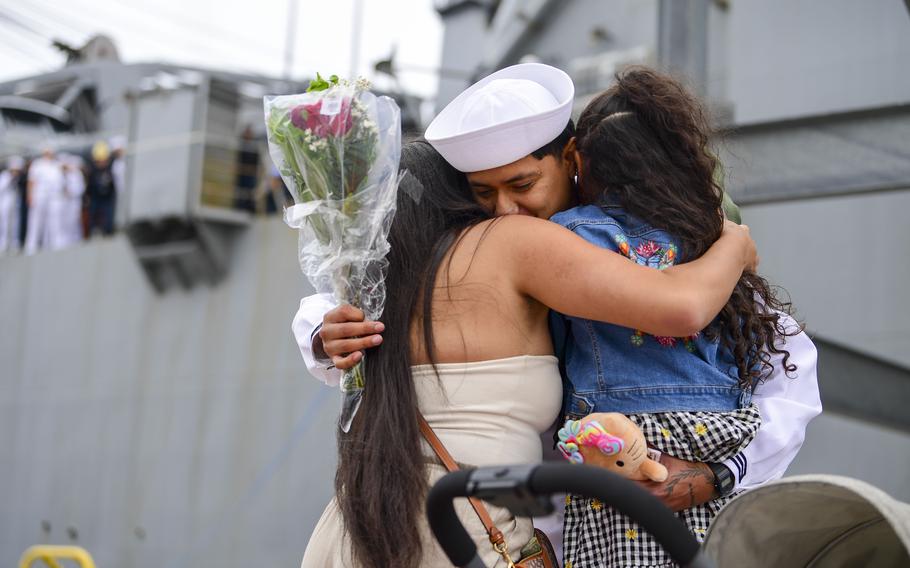 A sailor embraces loved ones