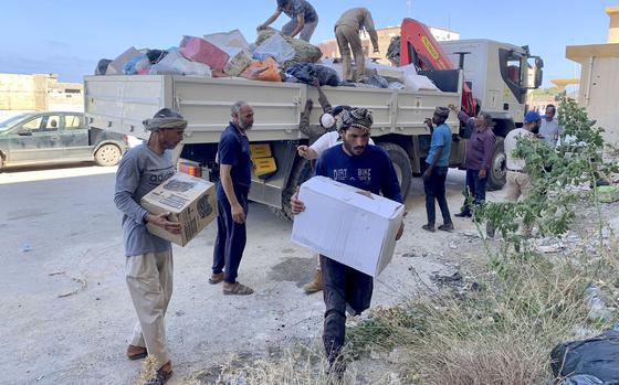 People deliver donated aid to a flash flood-destroyed city of Derna, Libya, Saturday, Sept. 16, 2023.