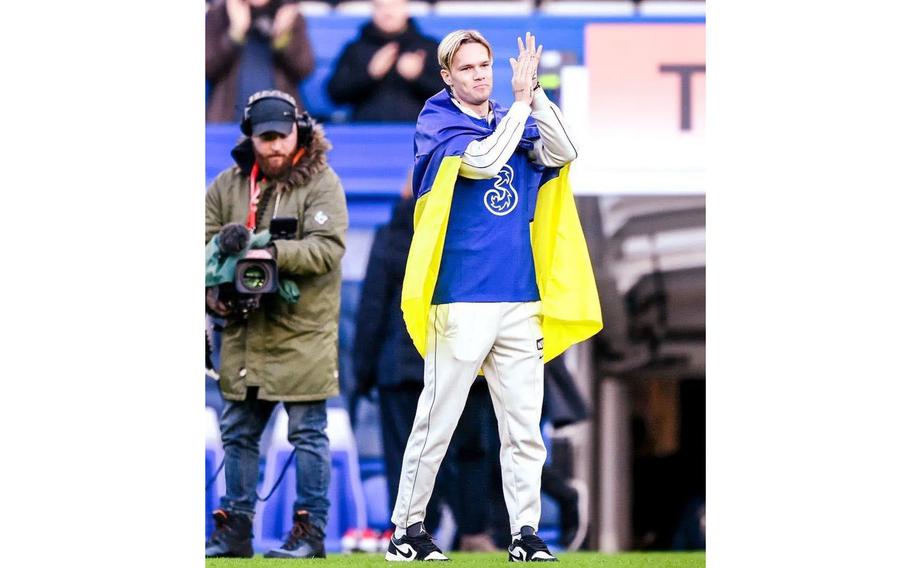 Mykhaylo Mudryk is draped in a Ukrainian flag Sunday, Jan. 15, 2023, as he is introduced to 40,000 fans at Chelsea’s Stamford Bridge stadium during half-time at the London club’s match against Crystal Palace.