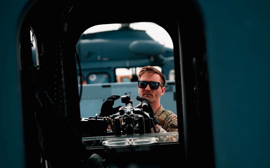 A flight engineer fixes an M240 machine gun onto a 550 HS MH-139 Grey Wolf helicopter.