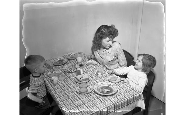 Aschaffenburg, Germany, Feb. 6, 1950: Betty Jo Fay, wife of First Sgt. Thomas H. Fay, of H Co. 18th Infantry, 1st Division, eats some soup and sandwiches with the couple's two children, Colleen, 5, and Richard, 3 at the family's kitchen table in their new apartment. The Fay family moved into one of the 156 newly constructed apartment units for servicemembers and their family in Aschaffenburg.

Read the accompanying article and see additional photos here. https://www.stripes.com/history/2022-06-13/eucom-housing-design-1950-6329852.html

META TAGS: history, european command, housing shortage post world war ii, military housing design, military housing europe, military housing