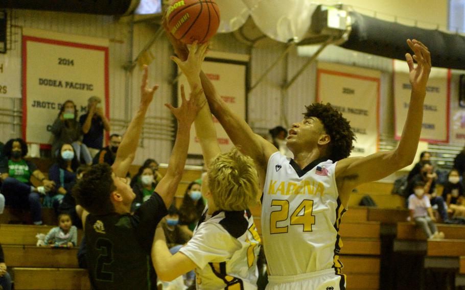 Kadena's Jeremiah Lewis reaches over Kubasaki's Levi Soto and Kadena's Harrison Vesely for a rebound during Friday's Okinawa boys basketball game. The Panthers won 43-35.