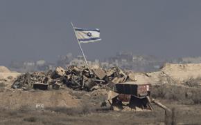 A flag rises from a pile of debris.