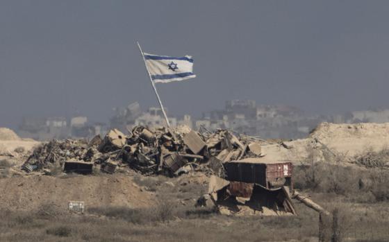 A flag rises from a pile of debris.