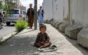 A child begs on a side walk in Kabul, Afghanistan, Sunday, May 22, 2022. Some 1.1 million Afghan children under the age of five will face malnutrition by the end of the year. , as hospitals wards are already packed with sick children . (AP Photo/Ebrahim Noroozi)