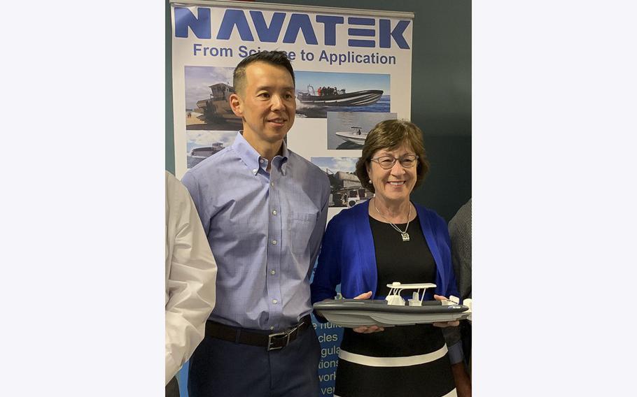 Sen. Susan Collins holds a miniature ship as she stands beside Martin Kao, the then-CEO of the engineering firm Navatek. Kao has pleaded guilty to illegally funneling more than $200,000 to Collins’ 2020 reelection campaign.