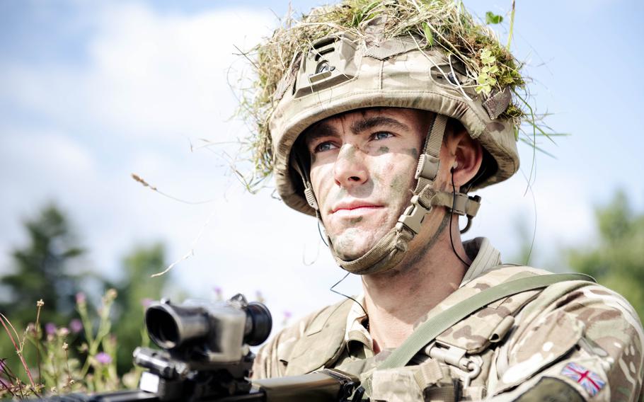 A British cadet with green face paint points his weapon during training.