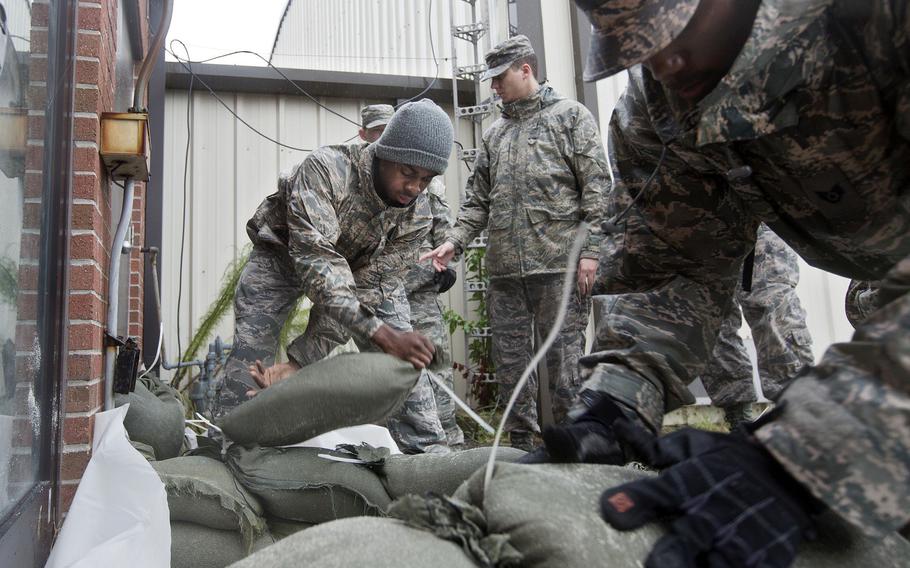 Airmen and volunteers place sandbags as heavy rain falls outside of a building at Langley Air Force Base in preparation for Hurricane Joaquin in October 2015.