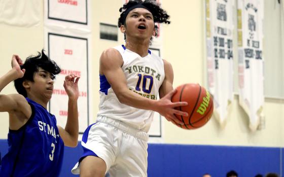 Yokota's Royce Canta drives to the basket againsts St. Mary's Towa Miyoshi during Thursday's Kanto Plain boys basketball game. The Titans won 67-63 in a rematch of last year's Far East Divisions I and II tournament champions.