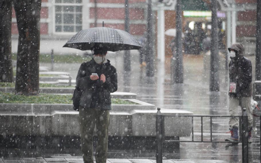 A man wears a mask while checking his phone outside Tokyo Station, Thursday, Feb. 10, 2022.