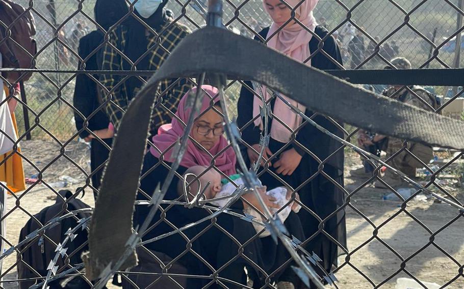 Afghan women tend to a baby in an undated photo taken through a chain link fence at Kabul, Afghanistan’s international airport. While an evacuation effort brought more than 123,000 civilians from the country on U.S. and coalition aircraft, not everyone the U.S. wanted to evacuate was able to leave, said Marine Gen. Frank McKenzie, head of U.S. Central Command, on Aug. 30, 2021.