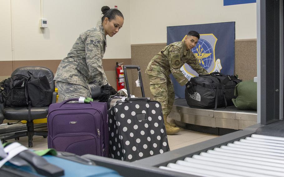 Airmen move baggage onto a conveyor belt ahead of a Patriot Express flight at Andersen Air Force Base, Guam, March 7, 2020.