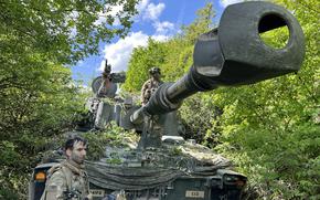 Army Staff Sgt. Matthew Daliege, an M109A7 Paladin section chief, left, and driver Pfc. Benjamin Cosby camouflage their mobile artillery system during exercise Combined Resolve at the Joint Multinational Readiness Center in Hohenfels, Germany, on May 20, 2025.