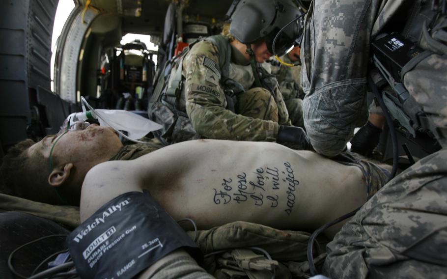 Pfc. Kyle Hockenberry, of 4th Squadron, 4th Cavalry Infantry Regiment, 1st Heavy Combat Brigade, 1st Infantry Division, who was injured in an improvised explosive device attack near Haji Ramuddin, is treated by flight medic Cpl. Amanda Mosher while being transported by medevac helicopter to the Role 3 hospital at Kandahar Air Field in Afghanistan on June 15, 2011. Throughout Hockenberry’s multiple surgeries and skin grafts, doctors have worked around his tattoo and left it intact. 