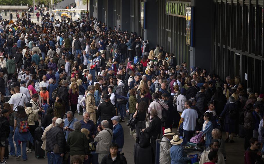 A huge crowd of people wait outside a closed train station in Barcelona.