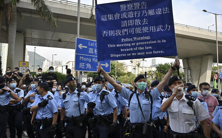 Police hold up warning banners to pro-democracy supporters gathering outside West Kowloon court in Hong Kong on March 1, 2021, ahead of court appearances by dozens of dissidents charged with subversion in the largest use yet of Beijing’s sweeping new national security law. 
