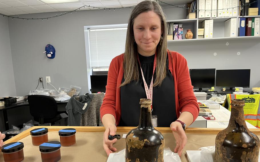 Lily Carhart, curator of preservation collections at George Washington’s Mount Vernon, shows historic bottles recently found buried there. The liquid and cherries inside were removed and placed in small containers, at left. 