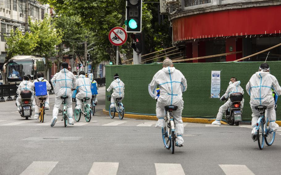 Members of a disinfection crew ride bicycles down a street in Shanghai on May 7, 2022.