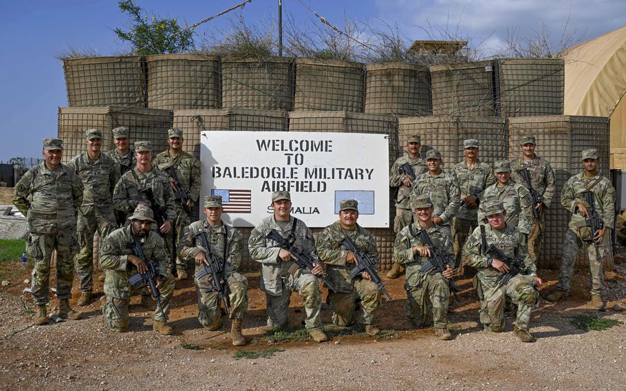 Soldiers pose for a photo, some are holding rifles.