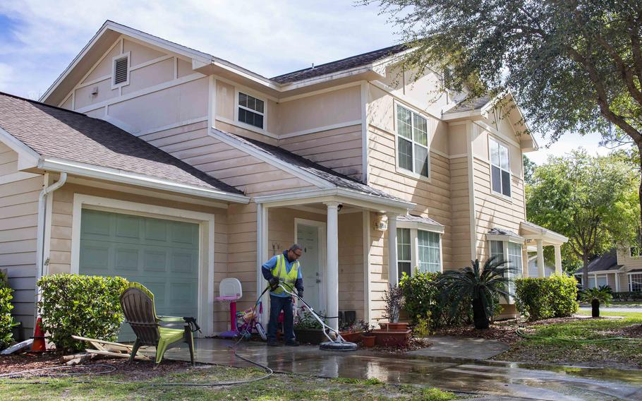 A maintenance worker for Balfour Beatty Communities in March 2019 power washes the driveway of a home at Marsh Cove, a military residential community at Naval Station Mayport, Fla. 