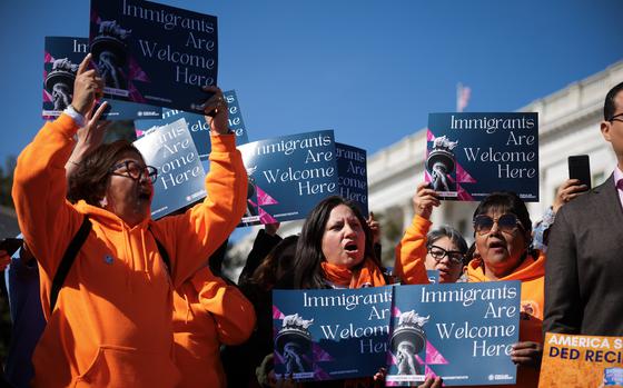 People hold up signs saying Immigration is welcome here.