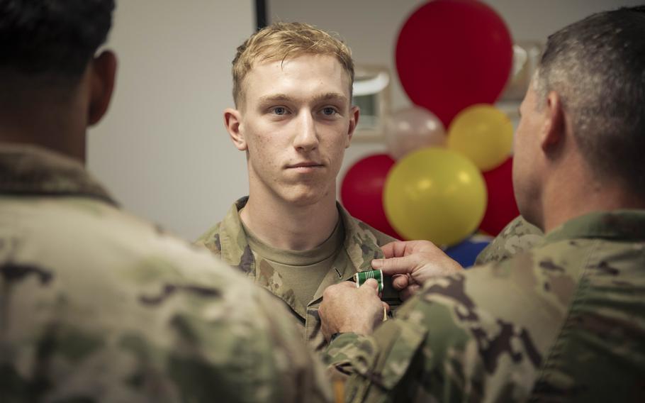 A soldier stands at attention as he receives a medal.